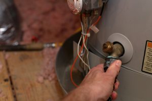 Hand attaches hose to water heater in home