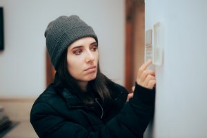 Woman Feeling Cold at Home Checking the Thermostat